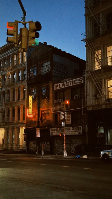 Nighttime street scene in Soho showing a multi-story building with dark, weathered brick and large windows, illuminated by streetlights and neon signs. A prominent vertical neon sign reading 'PARK' is